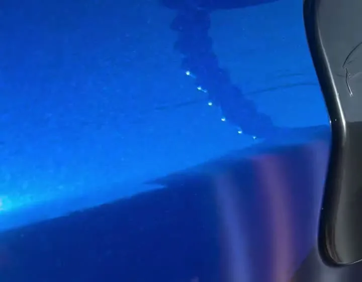 Blue vehicle panel showing dent distortion under reflection lighting