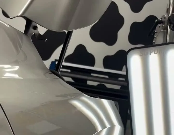 Silver vehicle panel under paintless dent repair inspection lighting